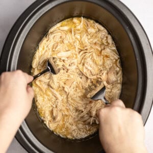 a slow cooker dinner of tender, juicy chicken that's being shredded in the crockpot for an easy weeknight dinner