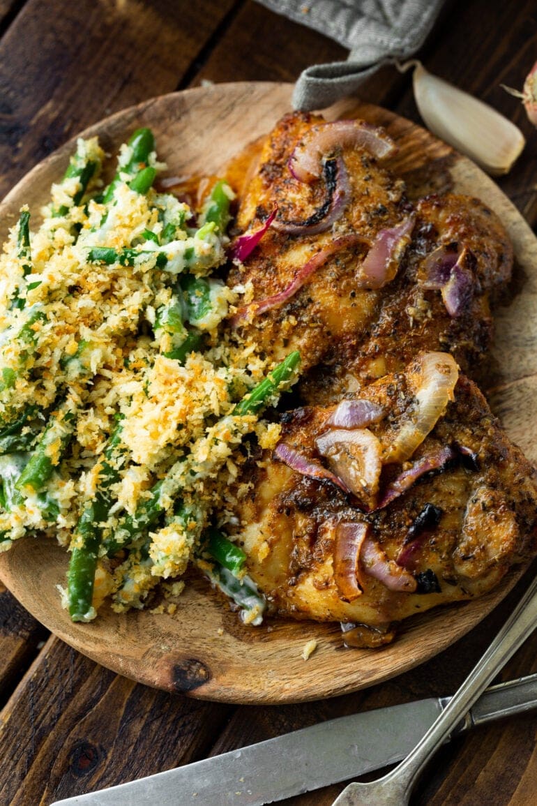 a juice baked chicken thigh topped with caramelized red onions with a side of green bean casserole
