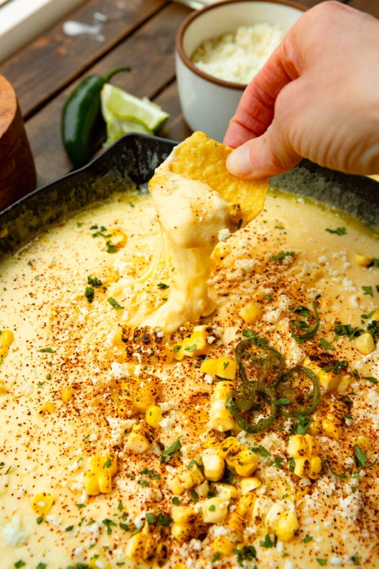 Skillet filled with creamy Mexican elote queso dip topped with roasted corn, cilantro, and cotija cheese.