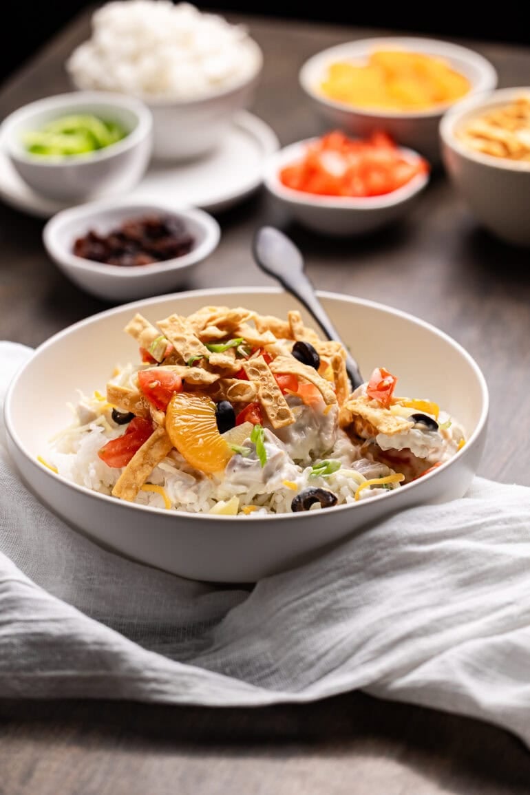 Ditch the soup cans and Chinese noodles, this is ultimate Hawaiian haystacks recipe and you're going to go crazy for them! Coconut milk chicken sauce draped over rice in a white bowl, finished with colorful toppings.