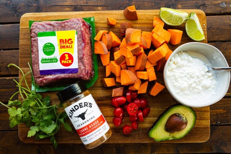 a photo of all the ingredients for a ground beef and sweet potato bowl including cubed sweet potatoes, avocado, cottage cheese, ground beef, cilantro, tomatoes and seasoning