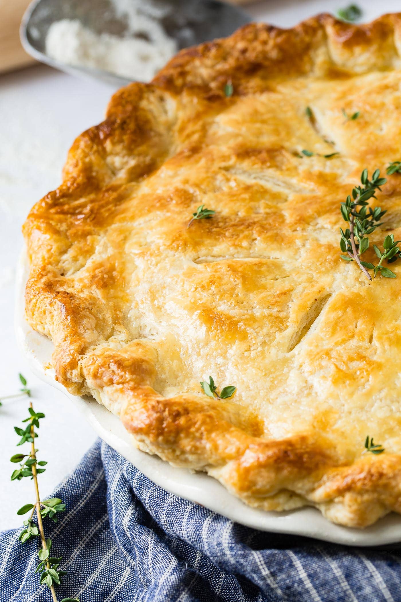 My Best Homemade Chicken Pot Pie Recipe A view of half of a chicken pot pie baked to a golden brown with a few sprigs of fresh thyme on top.