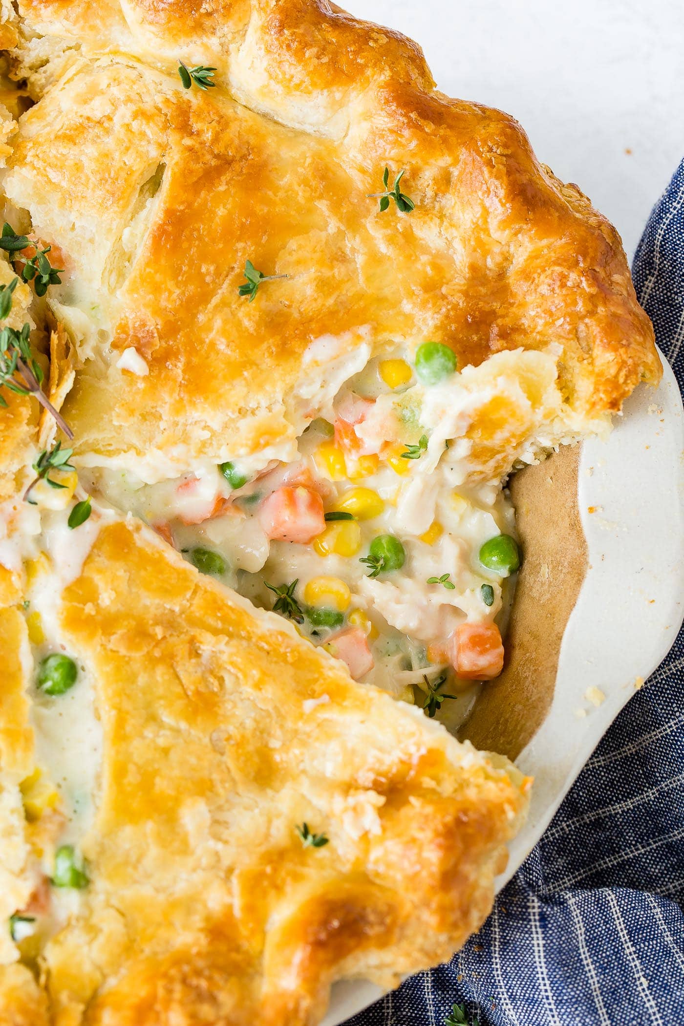 My Best Homemade Chicken Pot Pie Recipe A whole chicken pot pie with one piece cut showing the creamy sauce and carrots and peas and chicken in the filling.