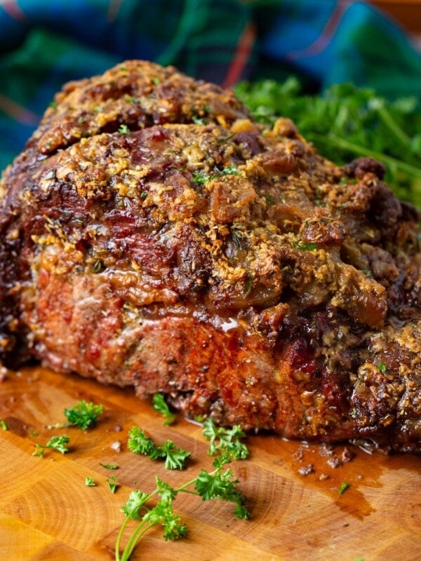 A photo of a whole smoked prime rib sitting on a cutting board garnished with fresh chopped parsley.