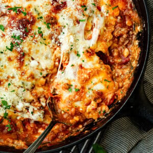 a photo of a serving of skillet lasagna being scooped out of a cast iron skillet