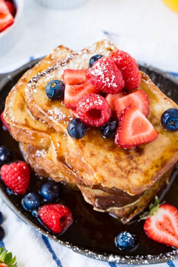 How to Make French Toast a stack of french toast covered in dripping syrup and fresh berries.