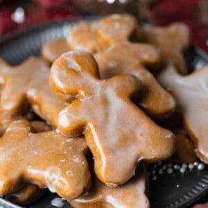 a photo of a lightly glazed gingerbread man cookie on top of a pile of other gingerbread men cookies.