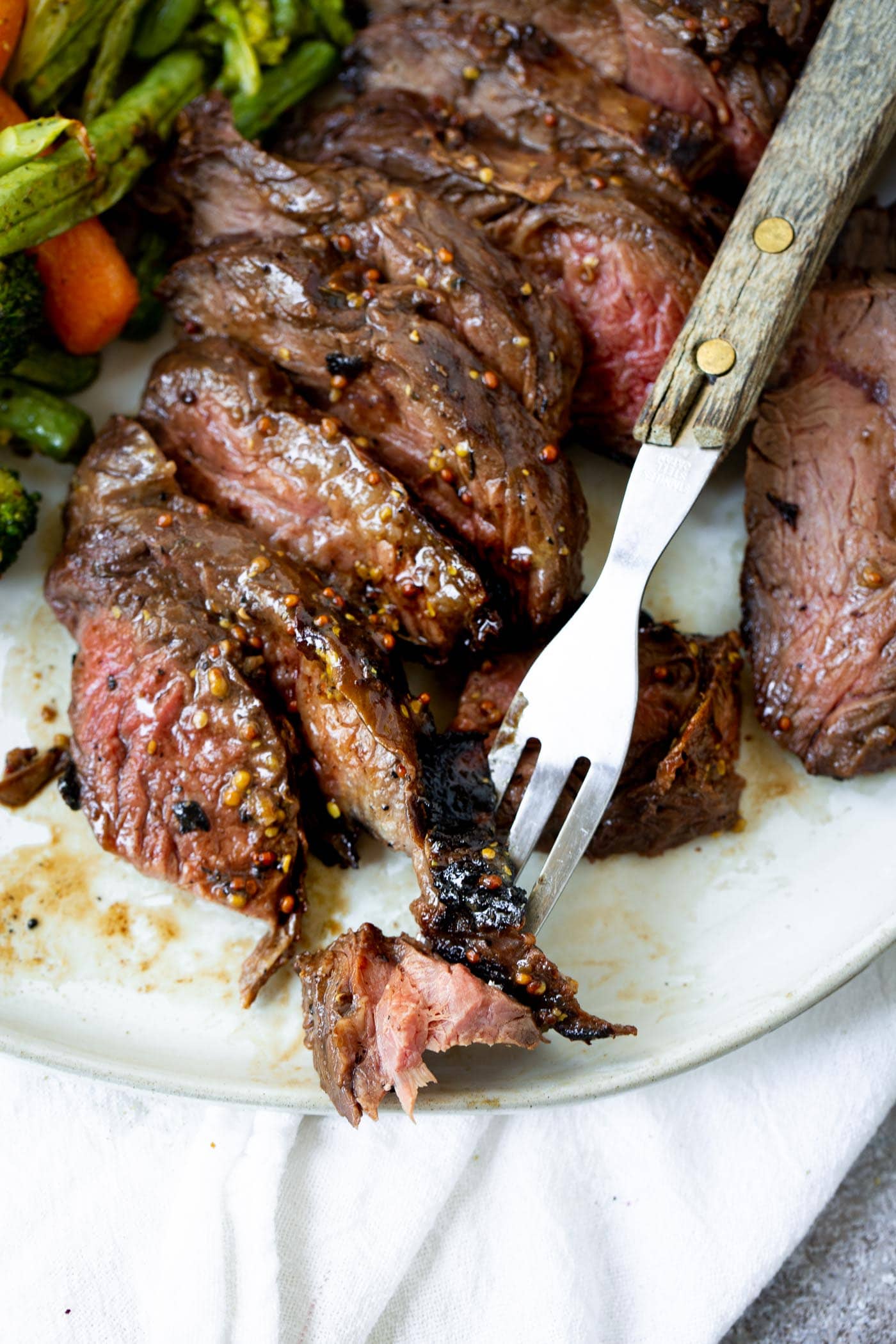The Best Steak Marinade A photo of a fork picking up one piece of sliced medium rare hanger steak.
