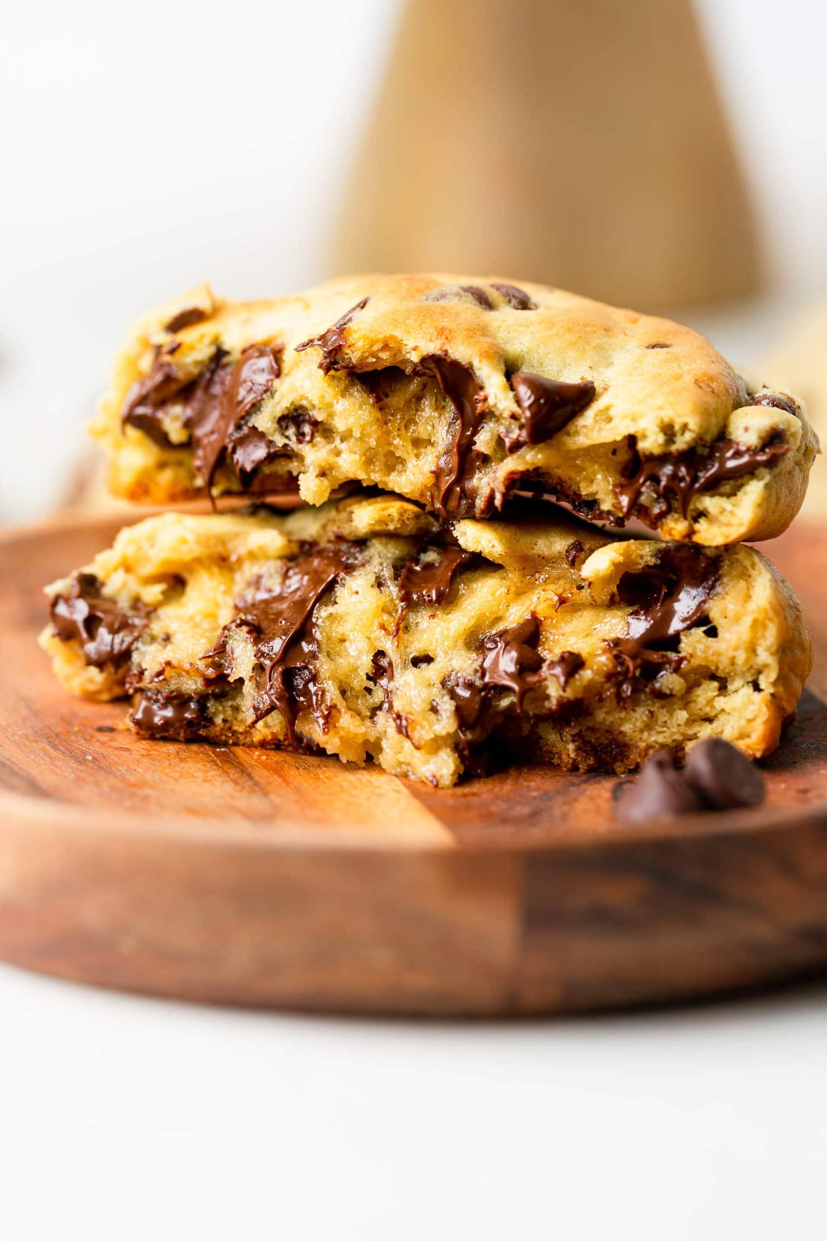 Levain Bakery Style Thick Chocolate Chip Cookies Recipe a photo of two thick gooey chocolate chip cookies that have been broken in half and stacked on top of each other.