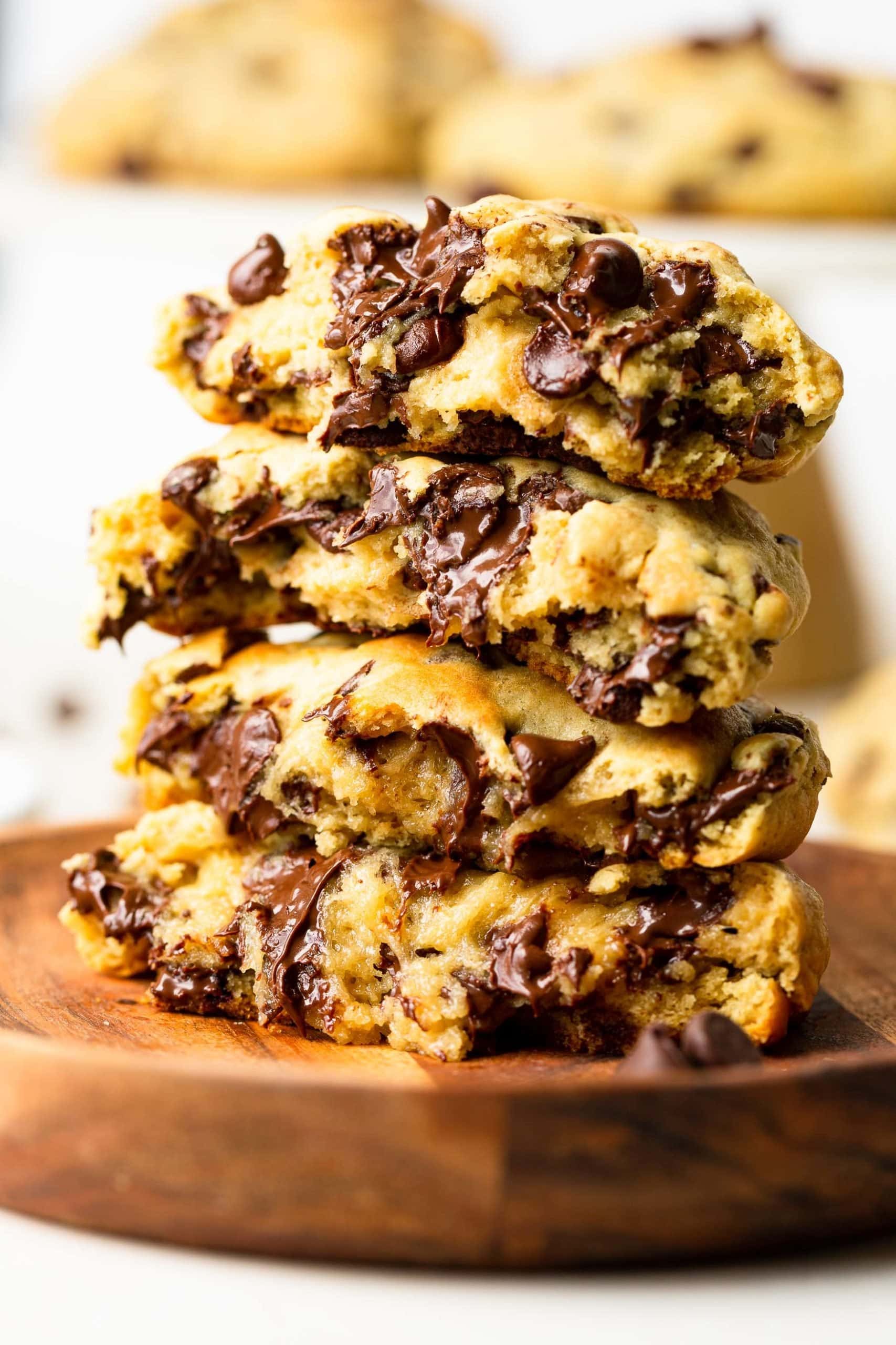 Levain Bakery Style Thick Chocolate Chip Cookies Recipe a photo of a stack of 5 thick and gooey chocolate chip cookies that have been broken in half.