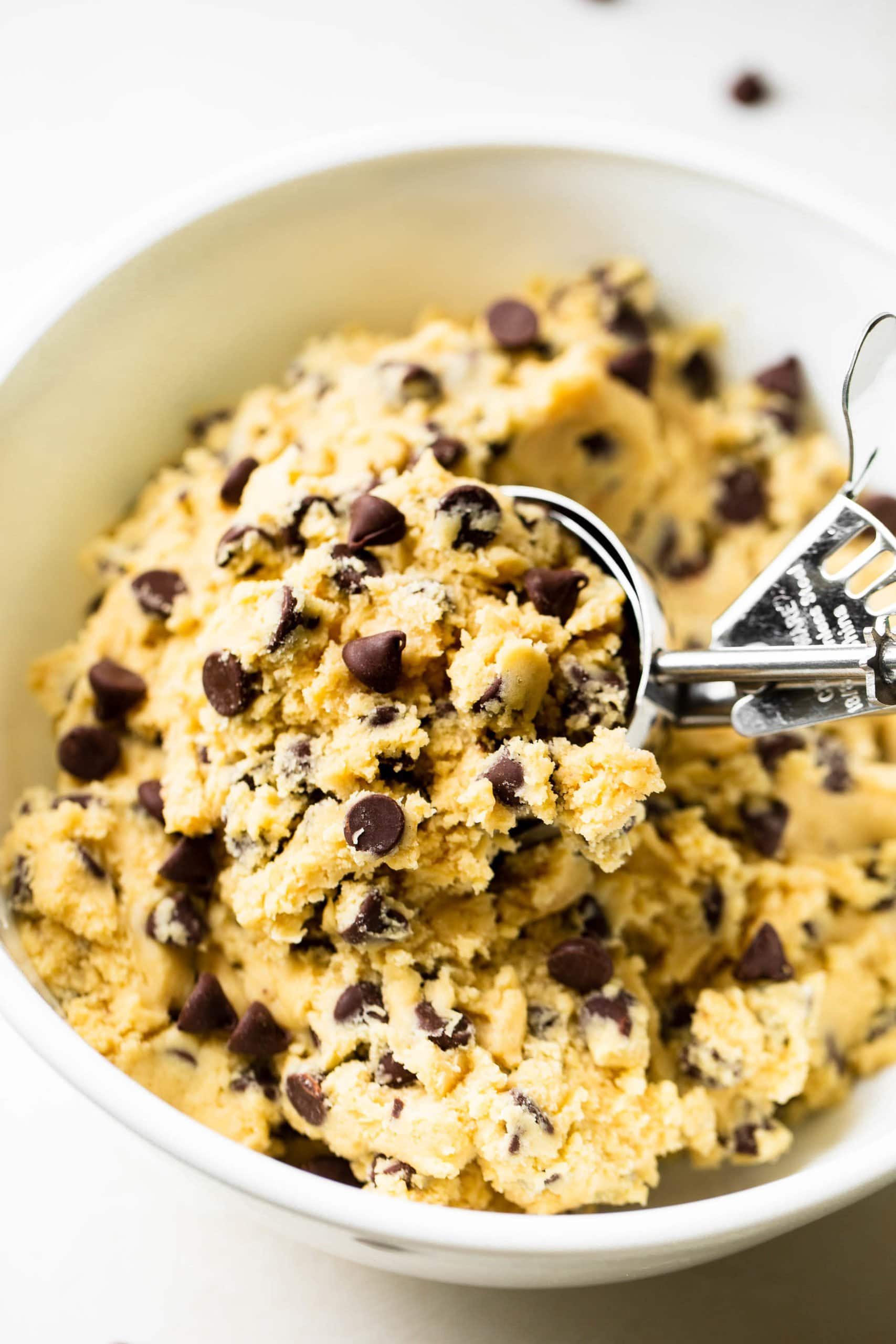 Levain Bakery Style Thick Chocolate Chip Cookies Recipe a photo of a large cookie scoop scooping out a big chunk of chocolate chip cookie dough.