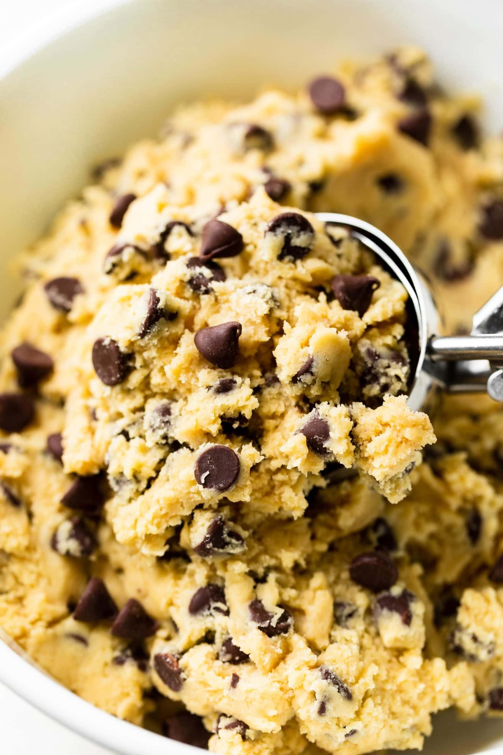 Levain Bakery Style Thick Chocolate Chip Cookies Recipe a photo of chocolate chip cookie dough being scooped out of a large bowl with a huge cookie scoop.